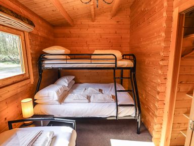 A wooden room with bunk beds a lamp and folded towels at iLodge 73 Kenwick near Louth