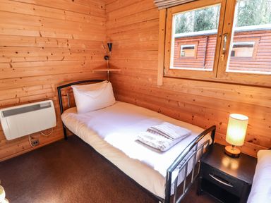 A bedroom with a single bed a bedside table with a lamp and a window at iLodge 73 Kenwick near Louth