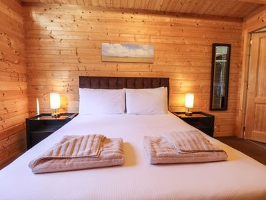 A bedroom with a double bed two bedside tables lamps and wooden panel walls at iLodge 73 Kenwick near Louth