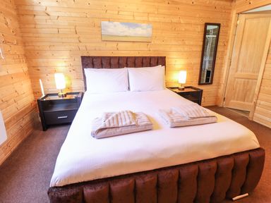 A bedroom with a double bed two bedside tables with lamps and wooden walls at iLodge 73 Kenwick near Louth