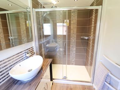 A bathroom with a sink on a wooden countertop a glass shower enclosure and a towel on a rack at iLodge 73 Kenwick near Louth