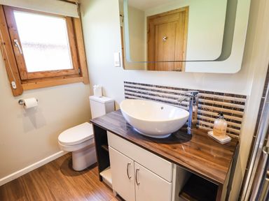 A bathroom with a toilet a wooden countertop with a white vessel sink mirror and window at iLodge 73 Kenwick near Louth