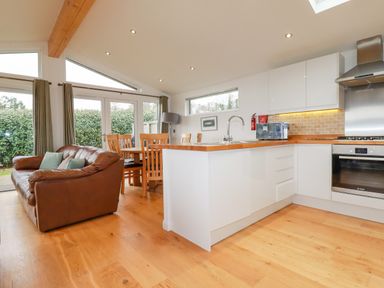 A kitchen and dining area with a brown couch wooden dining table chairs and white cabinets at 10 Faraway Fields in Dobwalls