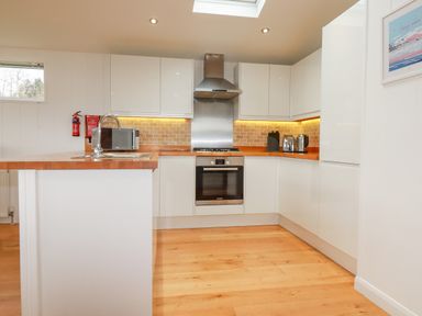 A kitchen with white cabinets a wooden countertop a microwave oven toaster kettle and an oven at 10 Faraway Fields in Dobwalls