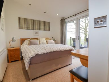 A bedroom with a bed and bedside table near glass doors at 10 Faraway Fields in Dobwalls