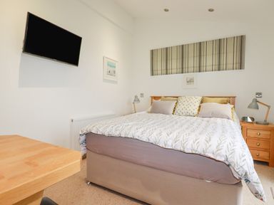 A bedroom with a bed and pillows a wooden desk a wall mounted television and framed pictures at 10 Faraway Fields Dobwalls