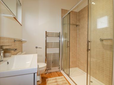 A bathroom with a sink, toilet, towel rack, shower enclosure, and a small window at 10 Faraway Fields in Dobwalls