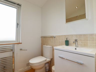 A bathroom with a toilet sink cabinet mirror and window at 10 Faraway Fields in Dobwalls