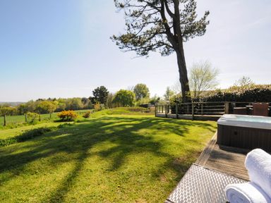 An outdoor garden area with grass trees a hot tub and chairs at 10 Faraway Fields in Dobwalls