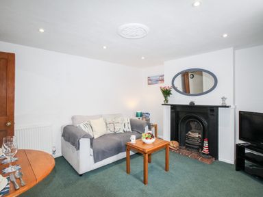 A living room with a sofa coffee table fireplace and television at Angel Cottage in Weymouth