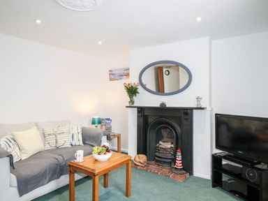 A living room with a sofa coffee table fireplace and television at Angel Cottage in Weymouth