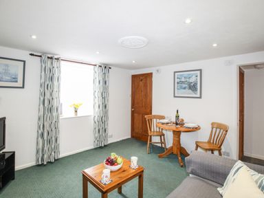 A living room with wooden door table chairs and patterned curtains at Angel Cottage in Weymouth