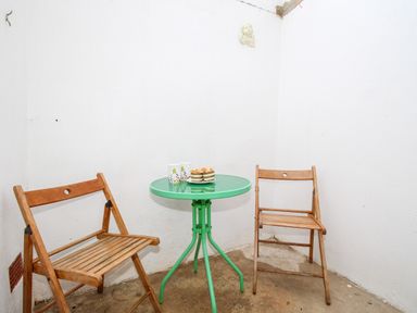 A small corner with two wooden chairs and a green round table with mugs and dessert at Angel Cottage in Weymouth