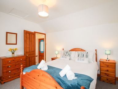 A bedroom with a wooden bed with white bedding and blue throw at Angel Cottage in Weymouth