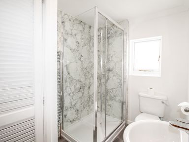 A bathroom with a glass shower enclosure a toilet and a sink at Angel Cottage in Weymouth