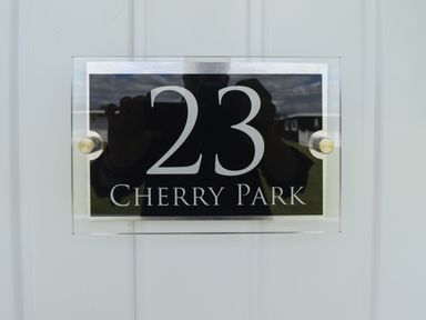 A house number sign showing 23 Cherry Park on a white door at 23 Cherry Park in Chapel St Leonards
