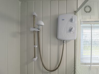 A shower unit with a handheld showerhead mounted on a white paneled wall at 23 Cherry Park in Chapel St Leonards