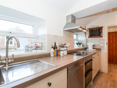 A kitchen with a sink stove oven dishwasher and countertop items at Garden Cottage in Chathill near Beadnell