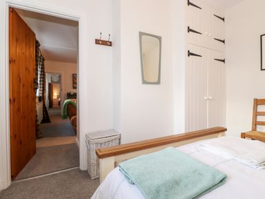 A bedroom with a bed towels mirror and wardrobe at Garden Cottage in Chathill near Beadnell