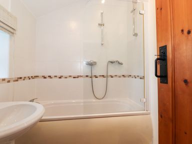 A bathroom with a bathtub shower combination and a sink at Garden Cottage in Chathill near Beadnell