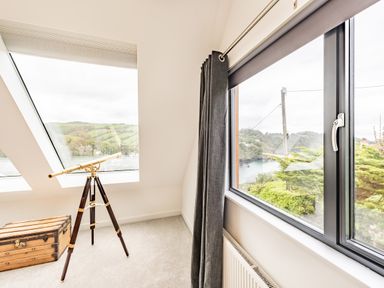 A room with a tripod telescope next to slanted windows and a wooden chest at Beach View in Combe Martin
