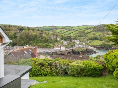 A hillside view overlooking houses, greenery, and a small bay with hills in the background at Beach View in Combe Martin