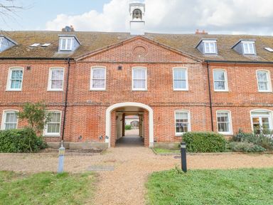 A brick building with multiple windows and a central archway leading through at Feathers Blythburgh in Reydon