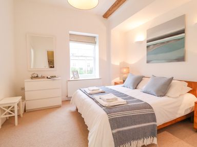 A bedroom with a bed with pillows and folded towels a dresser with a mirror and a window at Feathers Blythburgh in Reydon