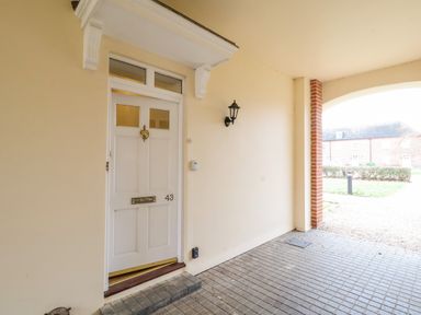 A white front door numbered 43 with a brass knocker and mail slot under a covered entrance at Feathers Blythburgh in Reydon