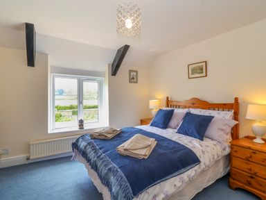 A bedroom with a double bed wooden furniture lamps and a window at Canny Croft in Chilton Polden near Street