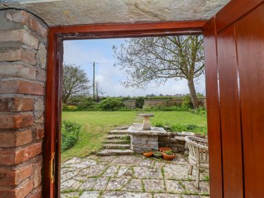 A garden with stone steps and birdbath viewed through a doorway at Canny Croft in Chilton Polden near Street
