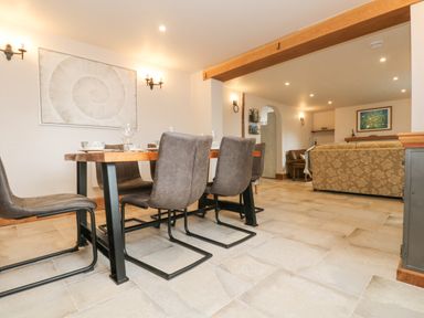 A dining area with a wooden table and chairs next to a living room with sofas at Woodbine Cottage Mylor Bridge Nr Falmouth