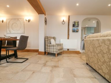 A living area with a dining table, chairs, a plaid armchair, and a beige patterned sofa at Woodbine Cottage Mylor Bridge Nr Falmouth