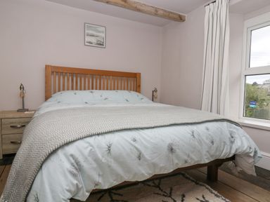 A bedroom with a wooden bed frame bedside tables lamps and a window at Woodbine Cottage in Mylor Bridge Nr Falmouth