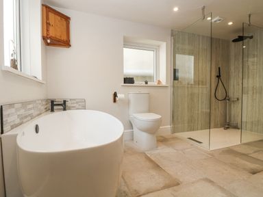 A bathroom with a bathtub toilet and a glass-enclosed shower at Woodbine Cottage in Mylor Bridge Nr Falmouth