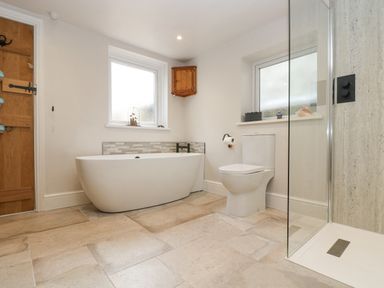 A bathroom with a freestanding bathtub toilet and a glass shower enclosure at Woodbine Cottage in Mylor Bridge Nr Falmouth