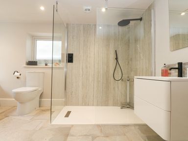 A bathroom with a toilet a walk-in shower with black fixtures and a white vanity at Woodbine Cottage in Mylor Bridge Nr Falmouth