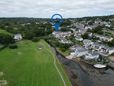 A village with houses near a river and a large grassy field with playground equipment at Woodbine Cottage in Mylor Bridge Nr Falmouth