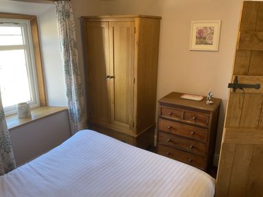 A bedroom with bed, wardrobe, and chest of drawers at Woodbine Cottage Mylor Bridge Nr Falmouth