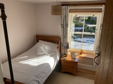 A bedroom with a bed and window at Woodbine Cottage, Mylor Bridge, Nr Falmouth