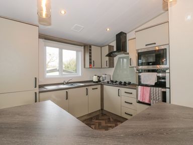 A kitchen with a gas stove oven microwave cabinets and a window at Gwydn Lodge in Downton Hampshire