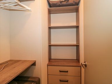 A closet with wooden shelves and drawers next to a countertop with hangers above at Gwydn Lodge in Downton Hampshire
