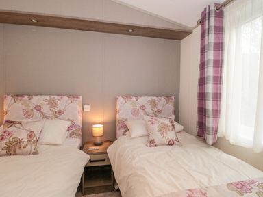 A bedroom with two single beds and a nightstand with a lamp between them at Gwydn Lodge Downton Hampshire