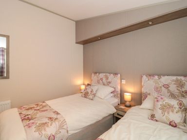 A bedroom with two single beds and floral bedding at Gwydn Lodge in Downton Hampshire