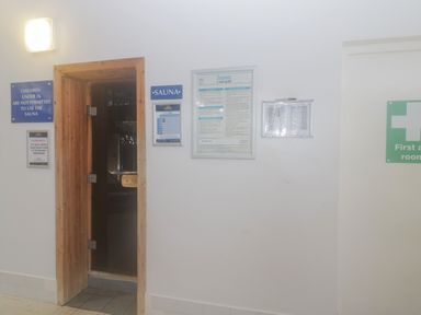 An entrance to a sauna with various informational signs on the wall including safety rules and a first aid room sign at Gwydn Lodge in Downton Hampshire