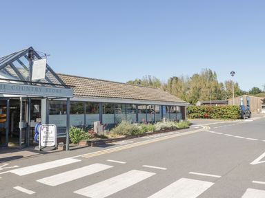 A country store building with a zebra crossing and a parking area in front at Gwydn Lodge in Downton Hampshire