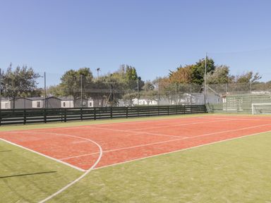 An outdoor sports court with red and green surface and a goalpost at Gwydn Lodge in Downton Hampshire
