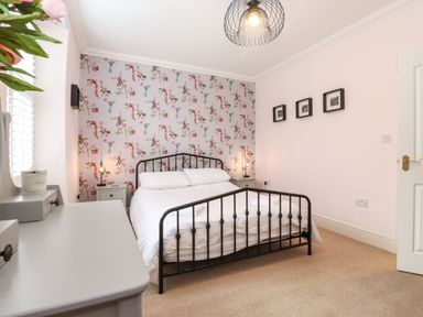 A bedroom with a metal bed frame and floral wallpaper at Snowflake Cottage in Windermere