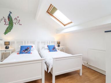 A bedroom with two single beds a skylight window and a peacock wall decal at Snowflake Cottage in Windermere