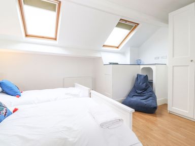 A bedroom with two single beds, skylight windows, a blue bean bag chair, and wooden floor at Snowflake Cottage in Windermere